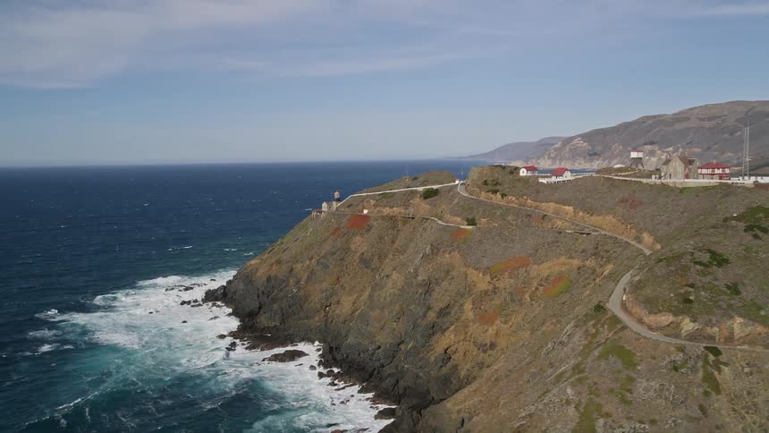 The white lighthouse with a red roof stands proudly on a cliff overlooking the vast ocean