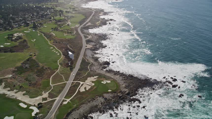 Aerial panorama of the extensive sea reaching the coast with an urban city surrounded by trees