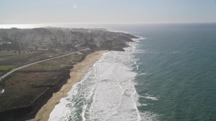 Aerial panorama of a vast sea that reaches a beach on the coast with an urban city
