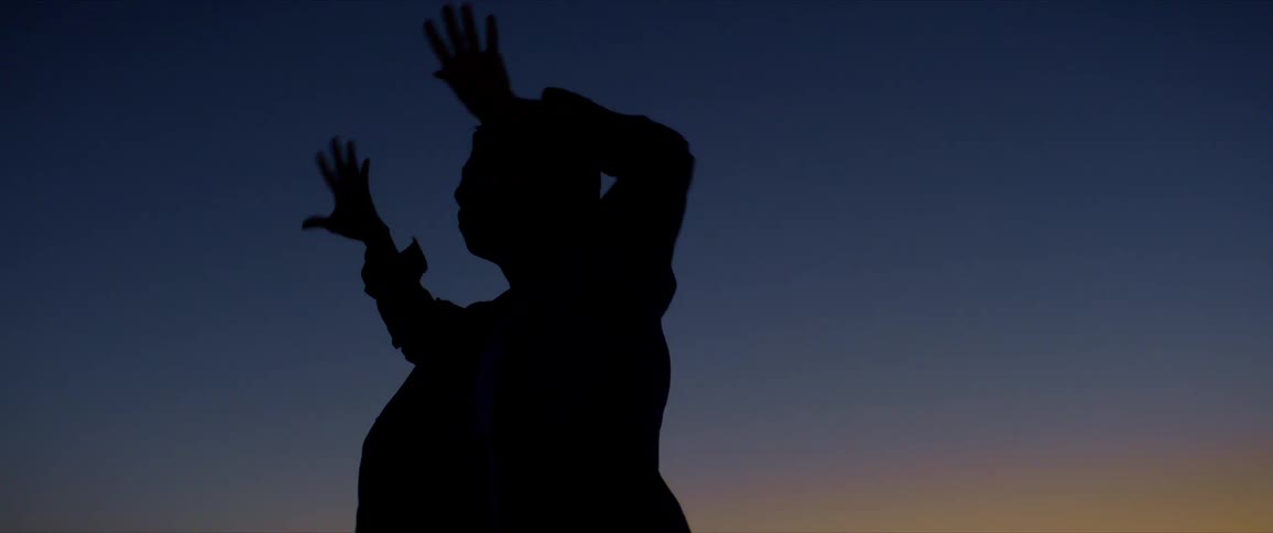 Silhouette of a man dancing against a late afternoon sky