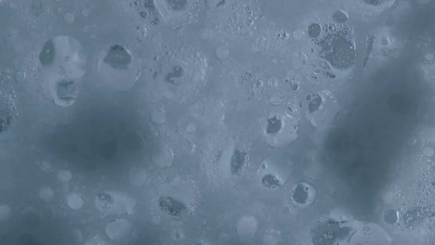 A white foam bubbles and pops