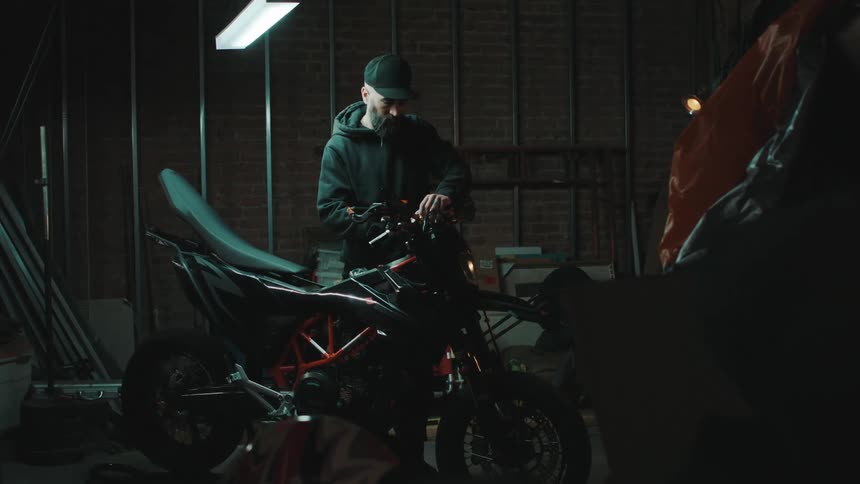 Mechanic with a wrench adjusting the handlebars of a motorcycle in a garage