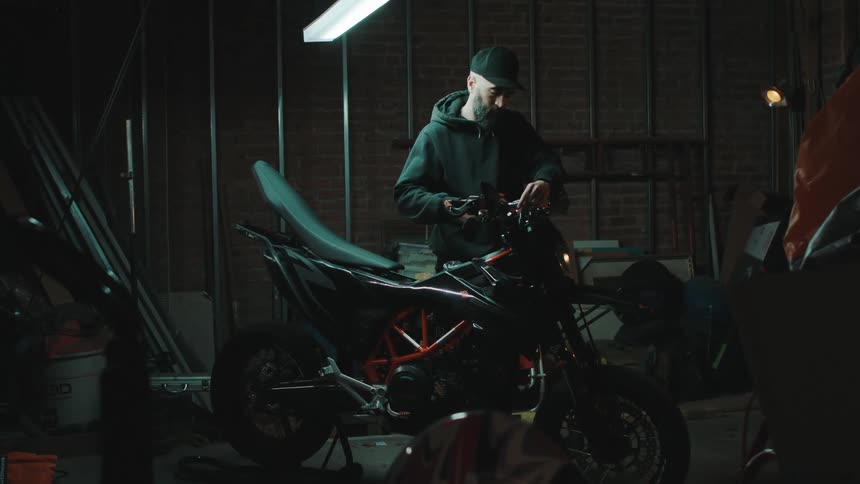 Man in a workshop tinkering with the handlebars of a motorcycle