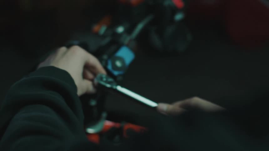 Mechanics hand holding an ordinary wrench and placing it on a bolt on a motorcycle