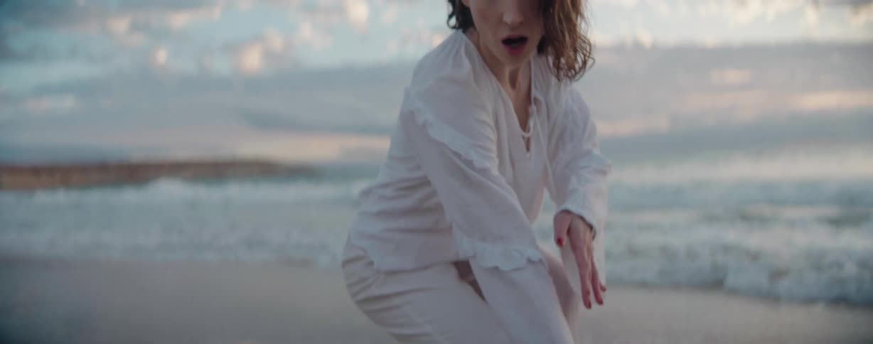 Woman dances on the beach on a windy day