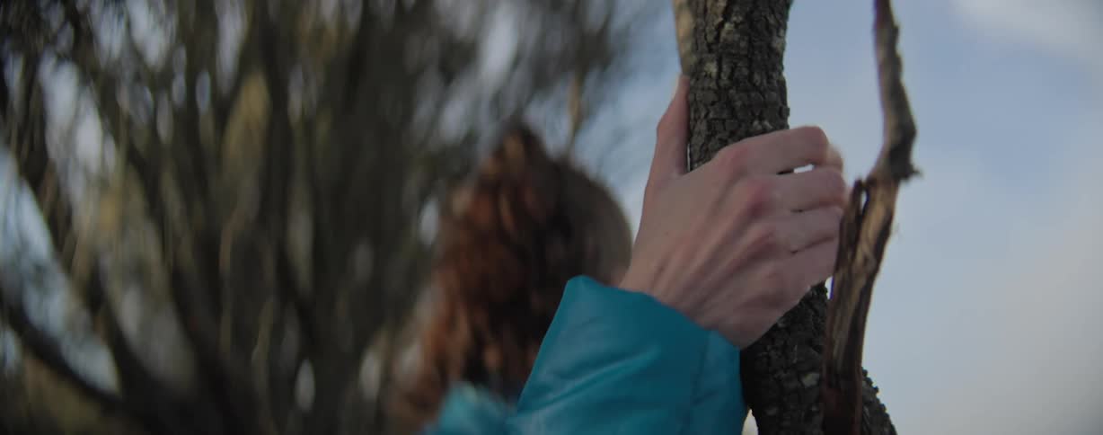 A woman grabs hold of a tree branch with her hand while hiking