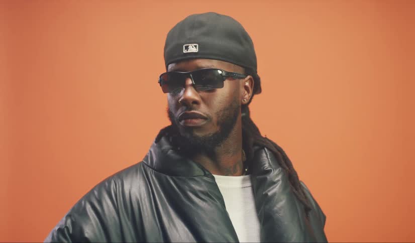 Portrait of a man in a cap and glasses backwards in a studio with an orange background