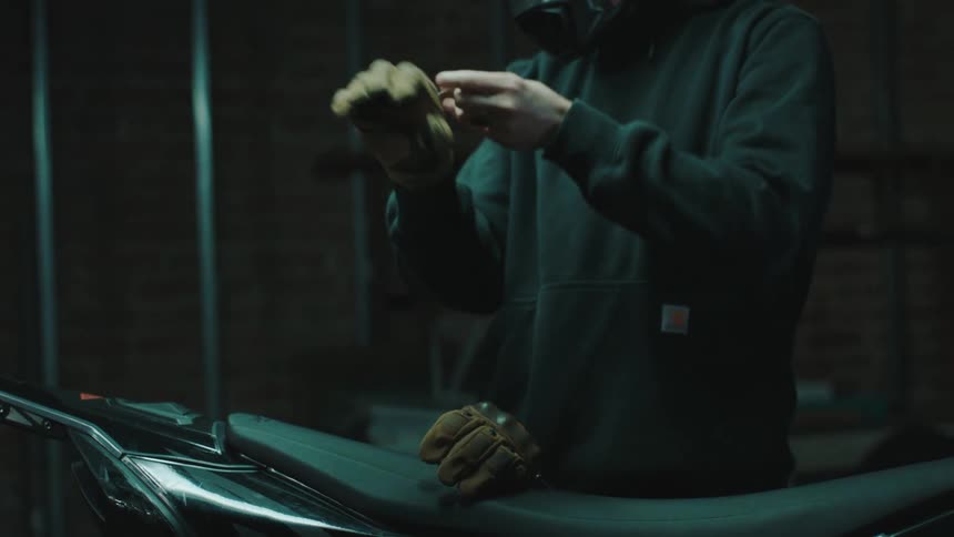 A man puts on his helmet and gloves to ride his motorcycle