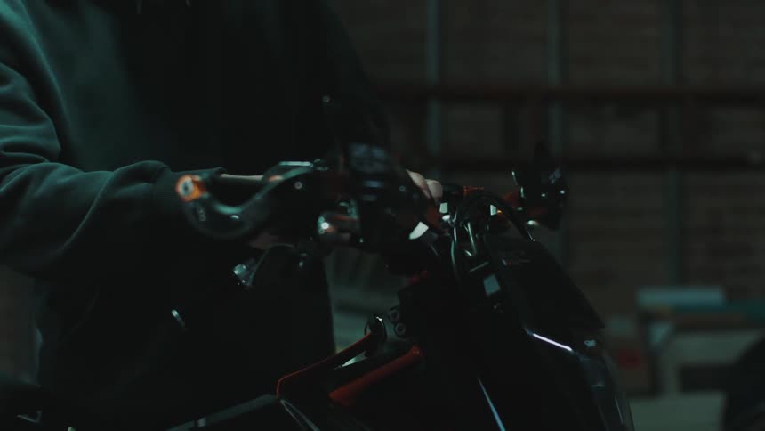 Man using a wrench on a motorcycle in a workshop