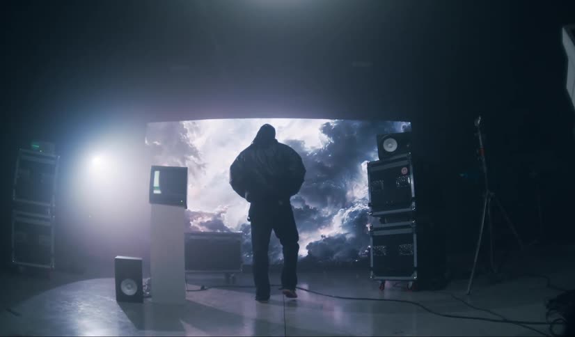 Man walking inside a studio with vintage televisions and a screen in the background