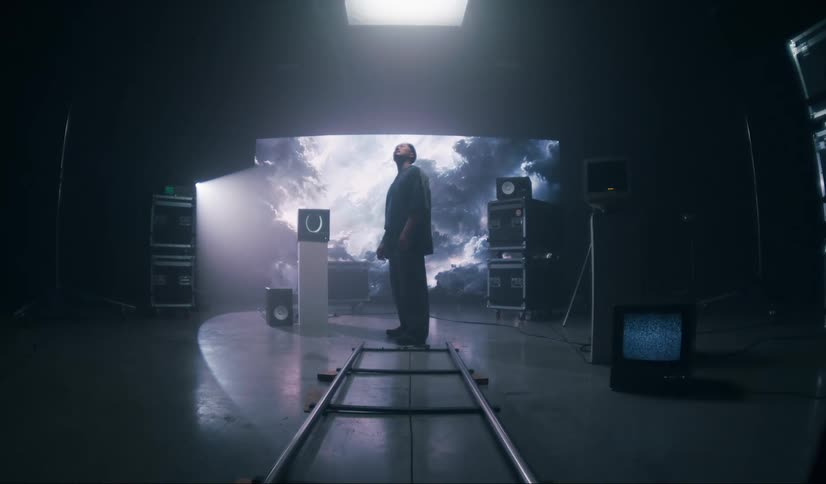 A man is standing in a studio with several screens and televisions with different images