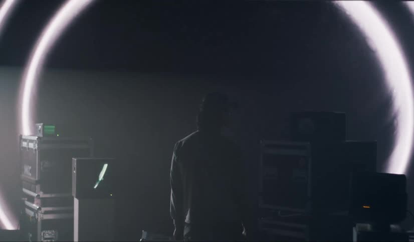 A silhouette of a person standing watching a huge screen with some videos playing quickly
