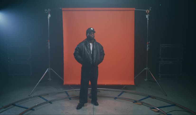 Model man in a cap and jacket in a studio with an orange banner in the background
