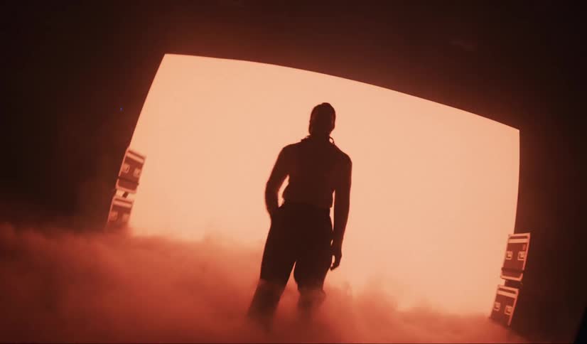 Man walks across foggy stage backlit by red lighting