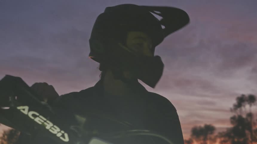 A person wearing a helmet on a vehicle at dusk