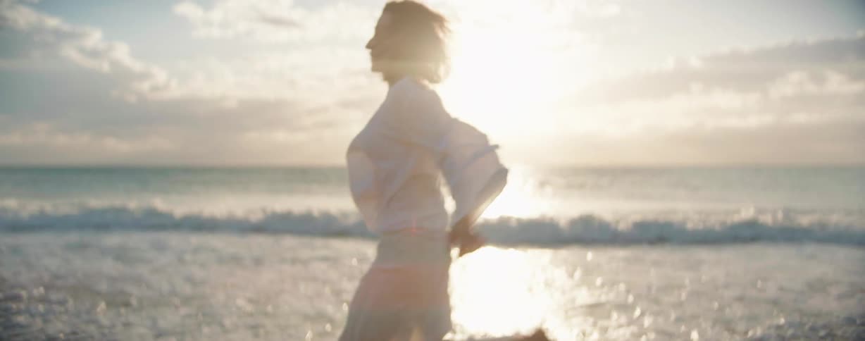 A female wearing all white is running on a beach