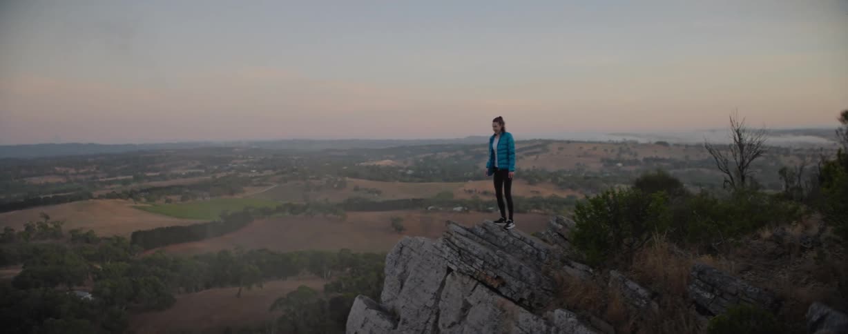 Woman hiking to top of a hiking trail throwing her arms up in achievement