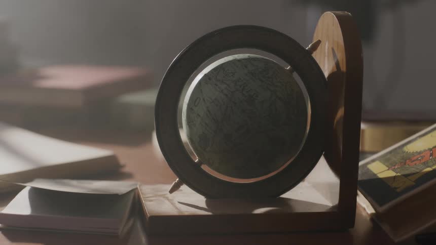 A small globe set on a stand over a desk in a dimly lit room