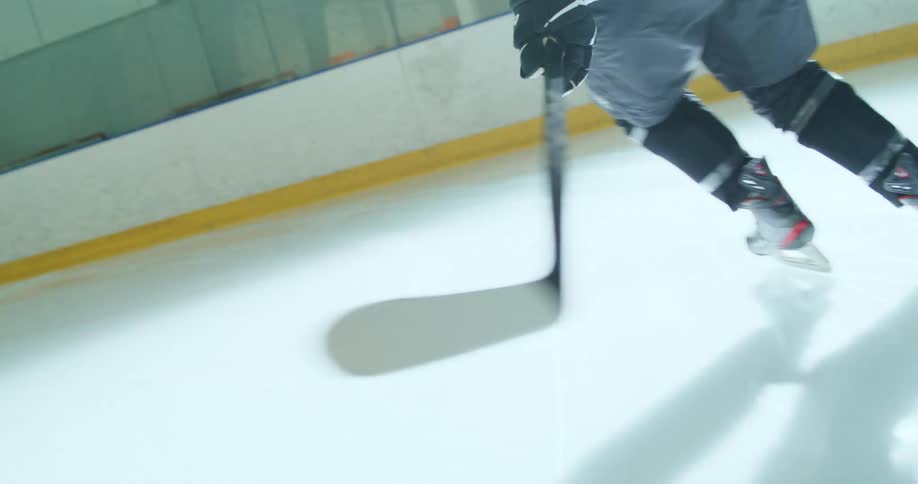 Female hockey player skating across a hockey court with her stick