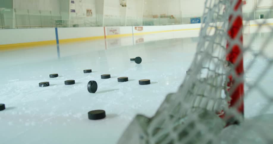 Pile of pucks thrown on the ice next to the goalie net