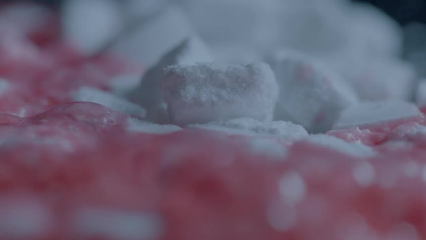 A red liquid reacts with a white powder and bubbles and foams