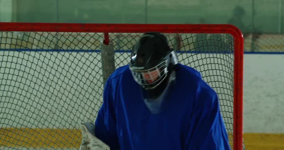 A goalie stands in front of a goal in an ice hockey rink