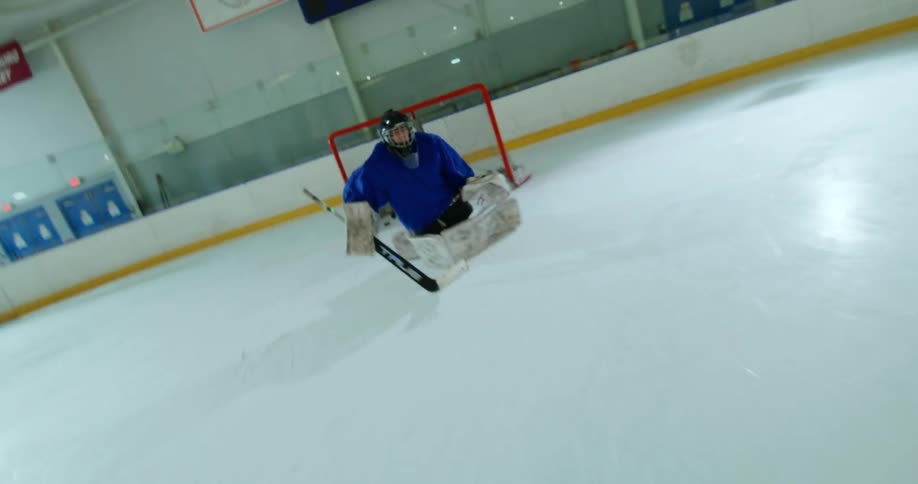 Point of view of a person scoring a point with a hockey stick against a goalie in blue