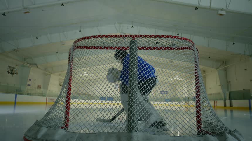 Hockey goalie practices on the ice near the goal