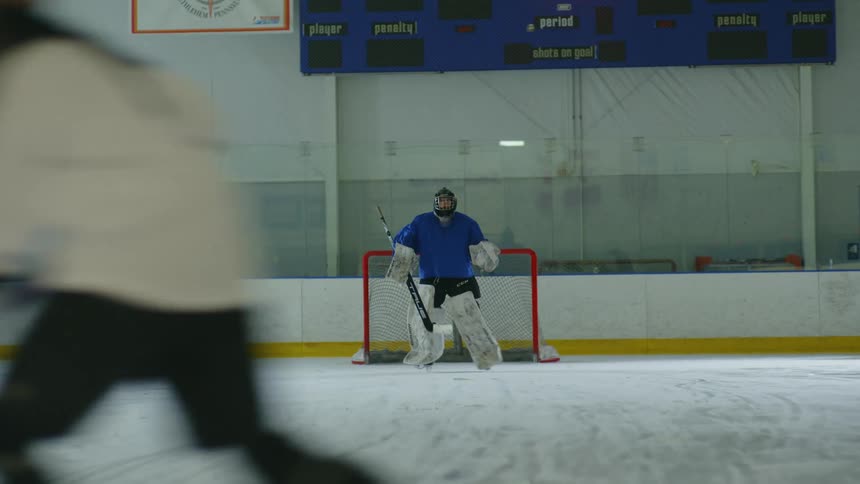 A woman shoots the puck but it is blocked by the goalie