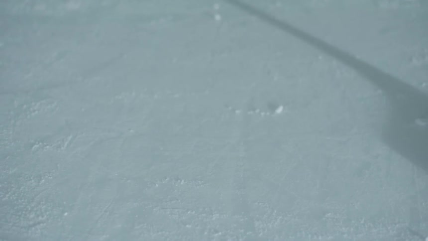 Closeup of the puck being handled by the hockey stick of a player