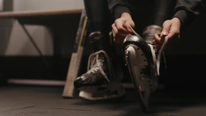 Persons hands tying his hockey boots
