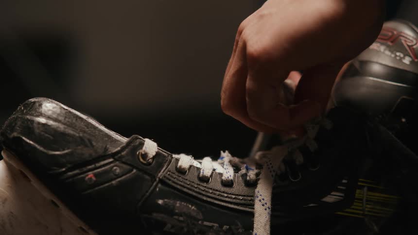 Person tying laces on hockey skates