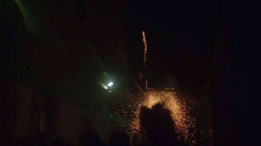 Fireworks exploding against a building at night