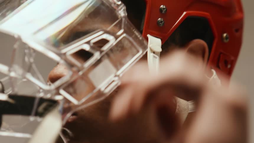 Close up of a young man wearing a hockey hellmet with a full face shield visor