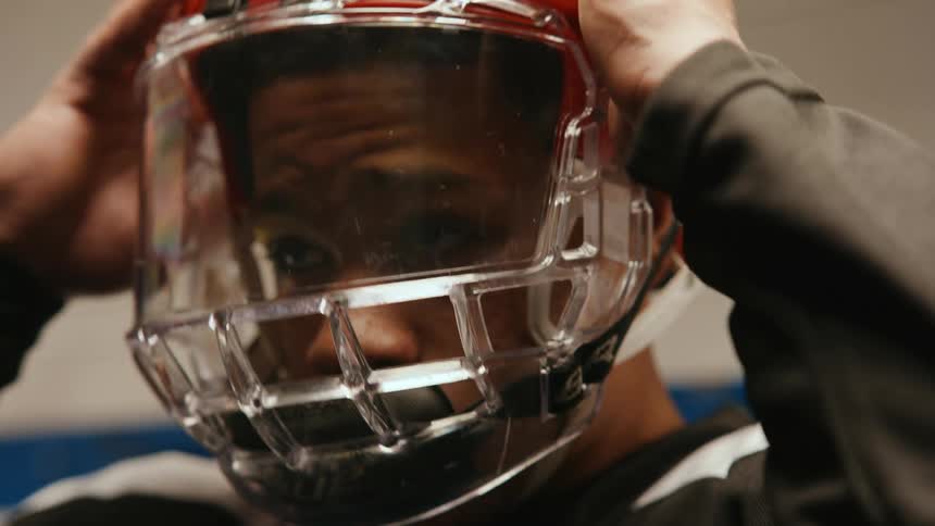 Male hockey player adjusts his helmet