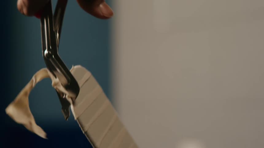 Hands with scissors cutting the tape around a hockey stick
