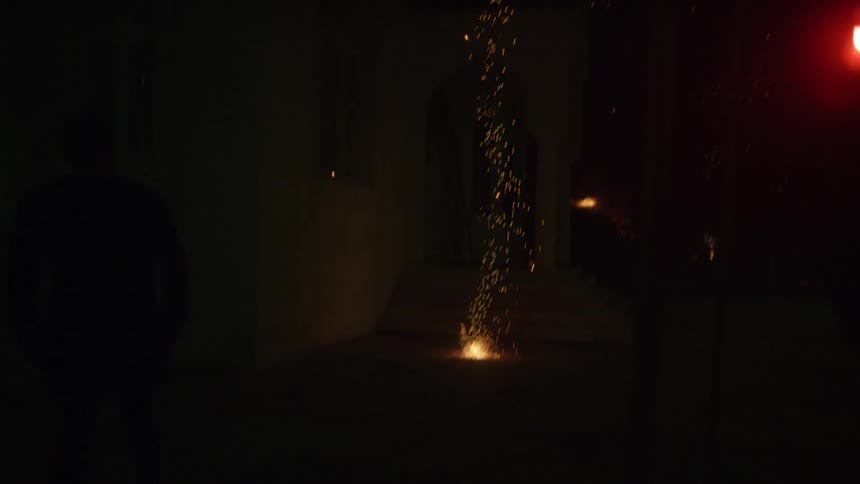 Fireworks fall around a man at night