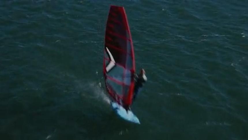 Aerial of hydrofoil windsurfer racing across the wate
