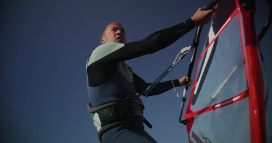 An Olympic windsurf athlete gets splashed by water while racing