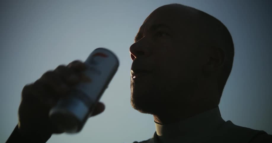 An athlete drinking an energy drink at sunset