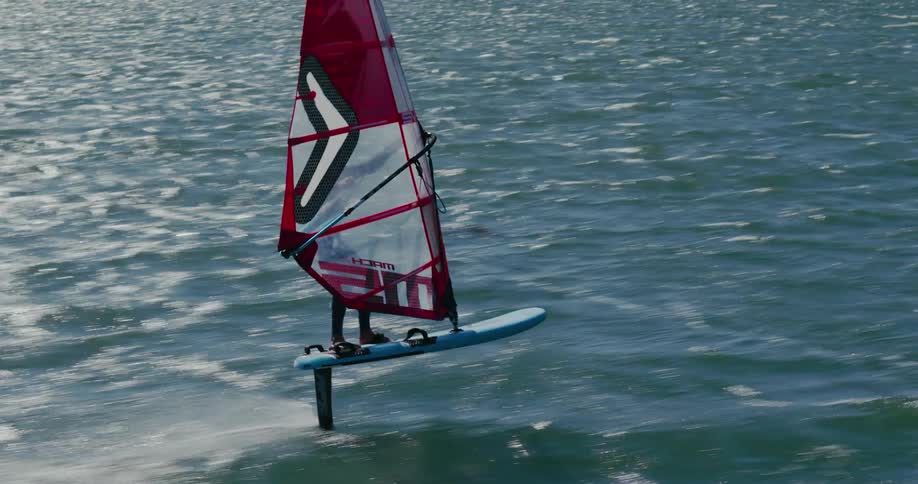 A windsurfer balances carefully as he sails at full speed