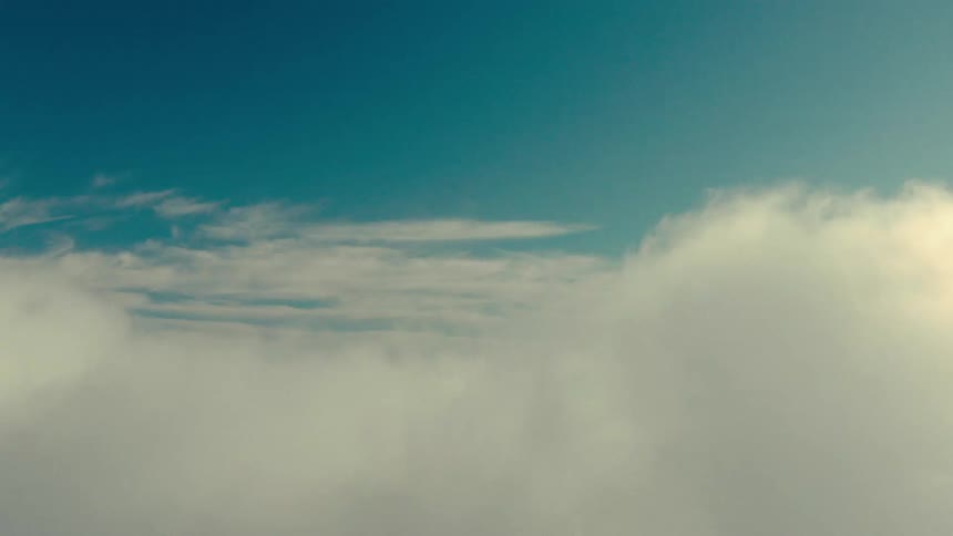 A dense white cloud passing through a blue sky