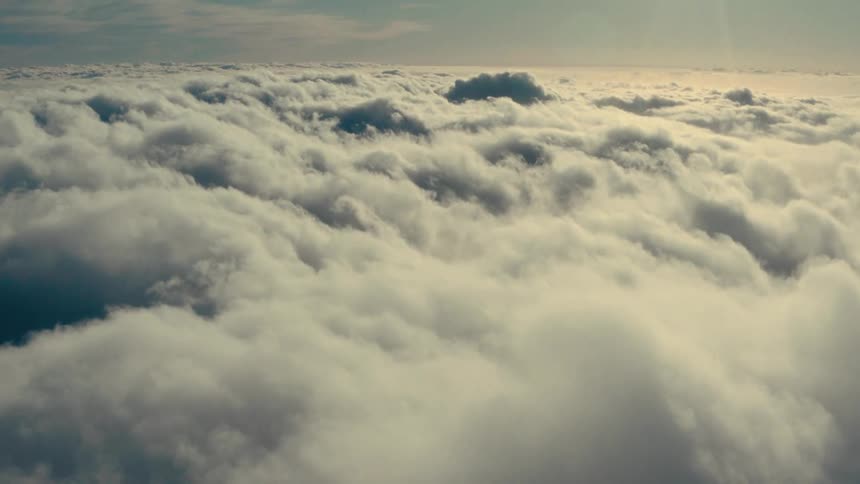 Aerial scenery of dense clouds clustered against a sunreflective sky
