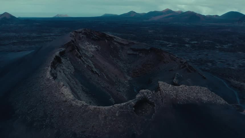 A stone mountain top in a desert region with other mountains in the background