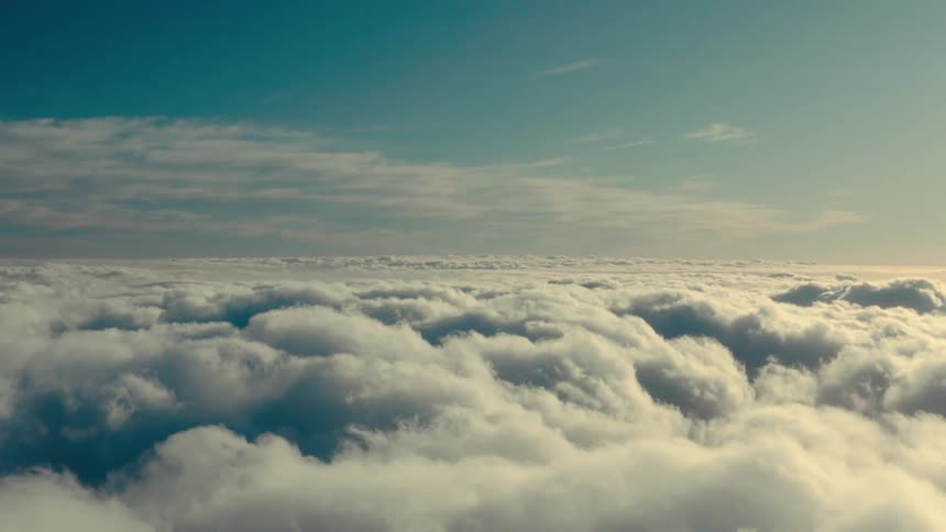 An aerial view of a horizon filled with white clouds at the bottom and a blue sky at the top