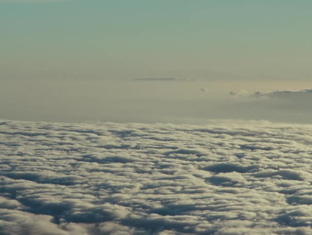 Sunlight tints atmosphere over flowing cloud layer