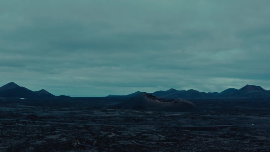 Panorama of a centered mountain with a crater and silhouettes of other mountains on the horizon