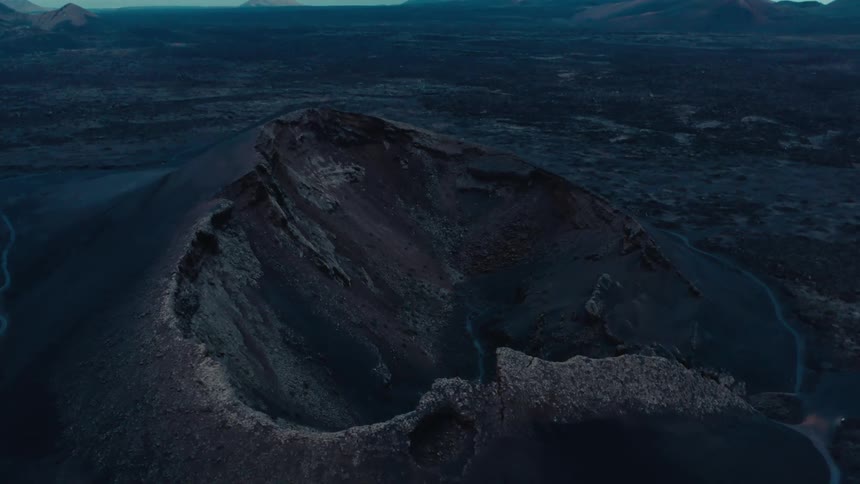 River flows through partially collapsed volcano in plain a distance from the mountains on the horizon