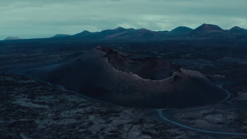 Aerial view shows a massive volcano with a wide crater at the summit