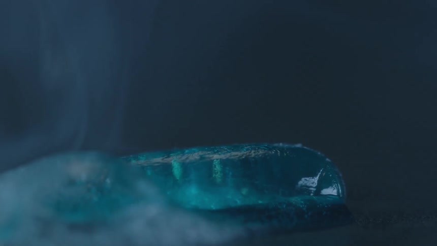 A blue, jell pill bubbles and boils away on a hot surface